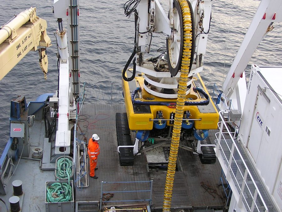 ROV inspecting a submerged repeater housing on the seafloor